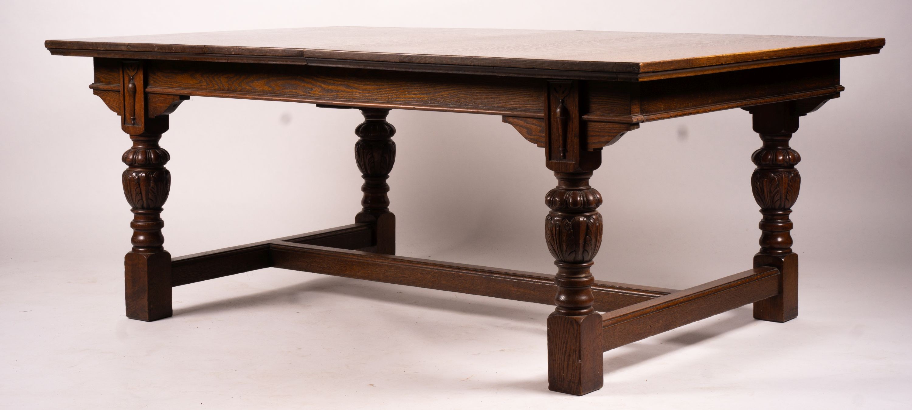 A 17th century style carved rectangular oak extending dining table with 'H' stretcher, 300cm extended, two spare leaves, width 121cm, height 75cm